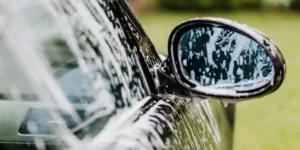 Professional car cleaning products arranged with a spotless luxury car in the background